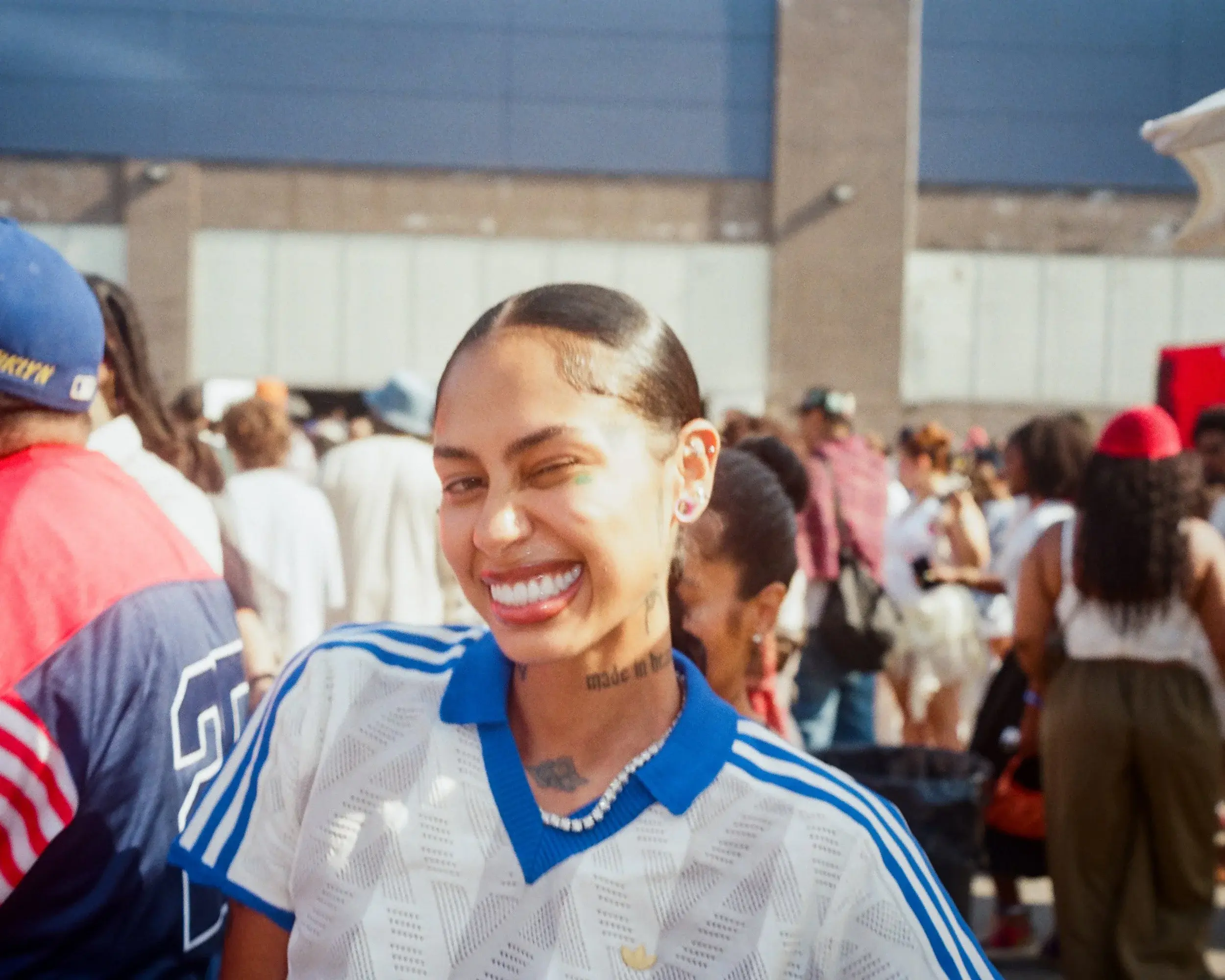 Candid portrait of a woman winking and grinning in a striped jersey amid a crowd
