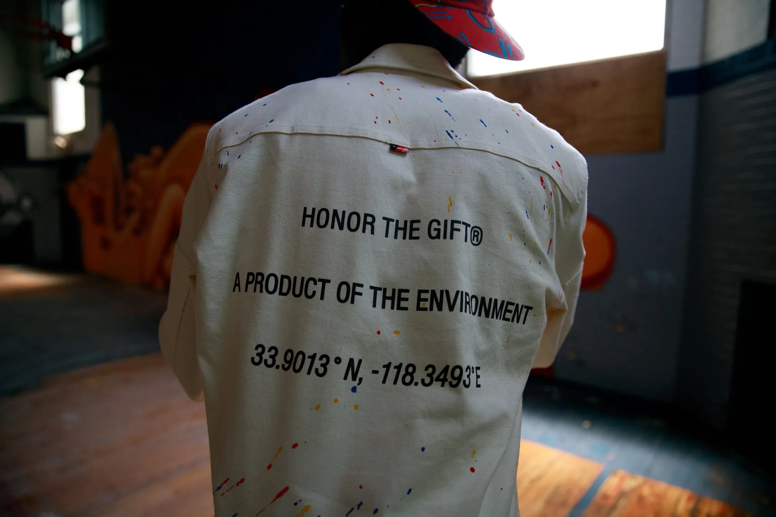 Back of a cream shirt with printed lettering and paint splatters, from a brand campaign