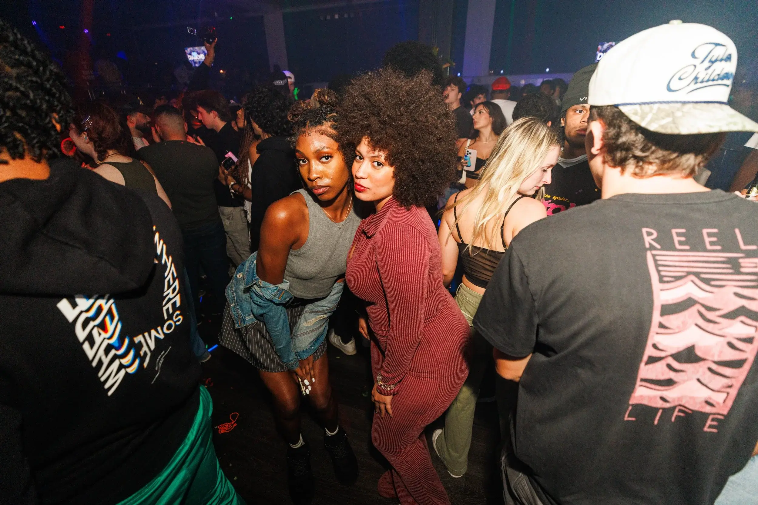 Two friends posing close together on a hazy, crowded dance floor