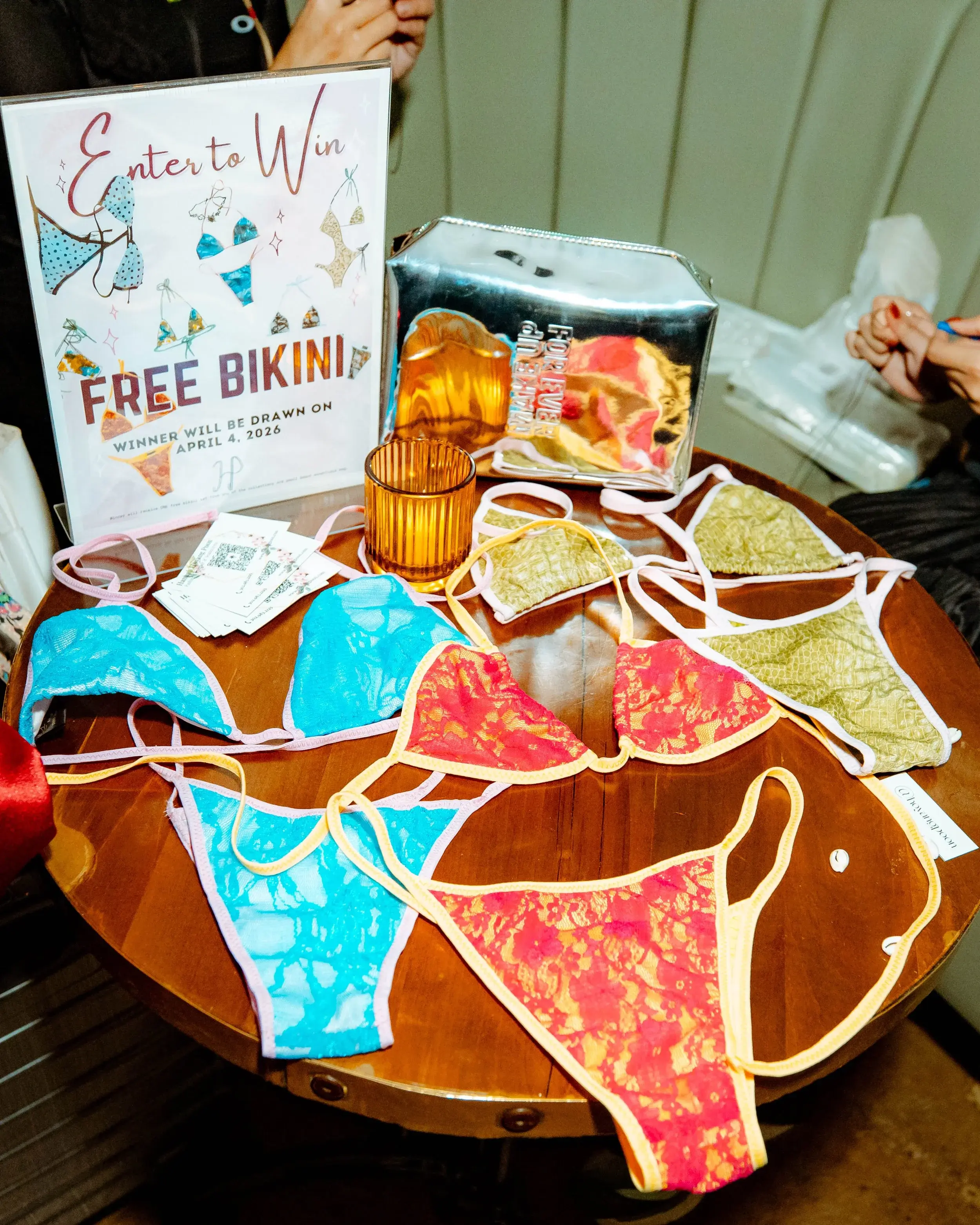 Colorful lace swimsuits and a raffle prize sign spread across a wooden table