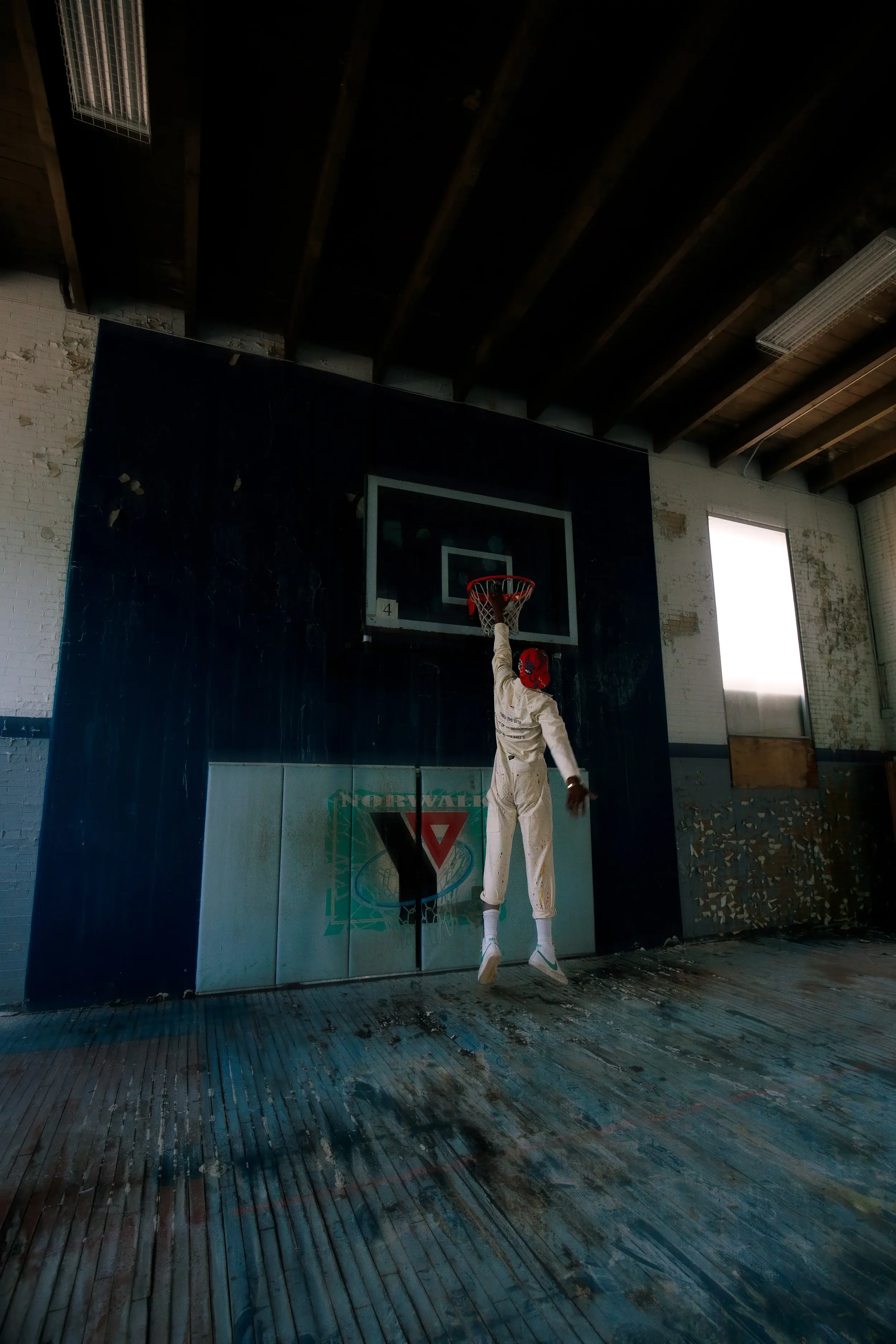 Model leaping toward the hoop for a dunk in a weathered indoor court
