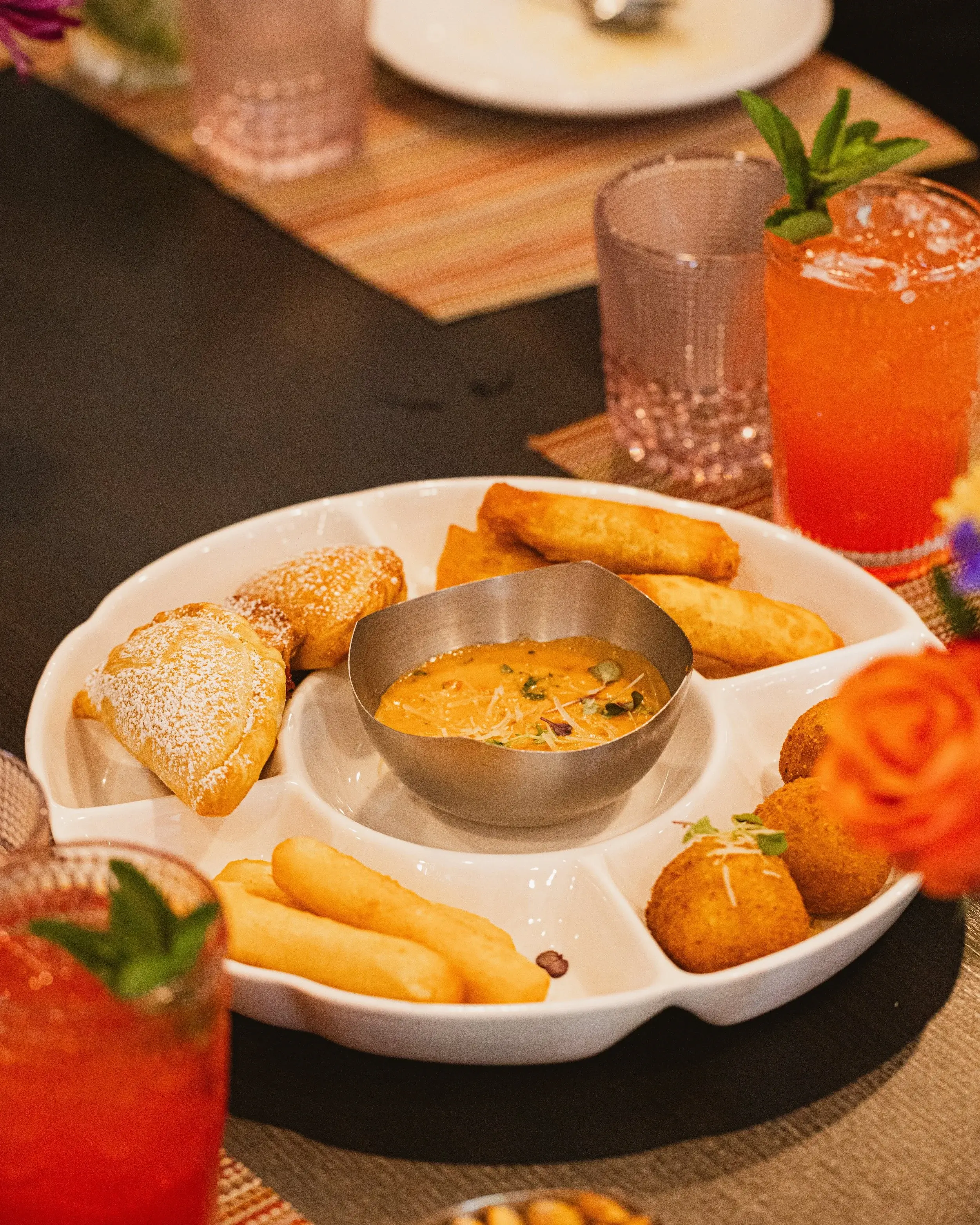 Foam-topped orange cocktail dotted with pink peppercorns on a candlelit dinner table