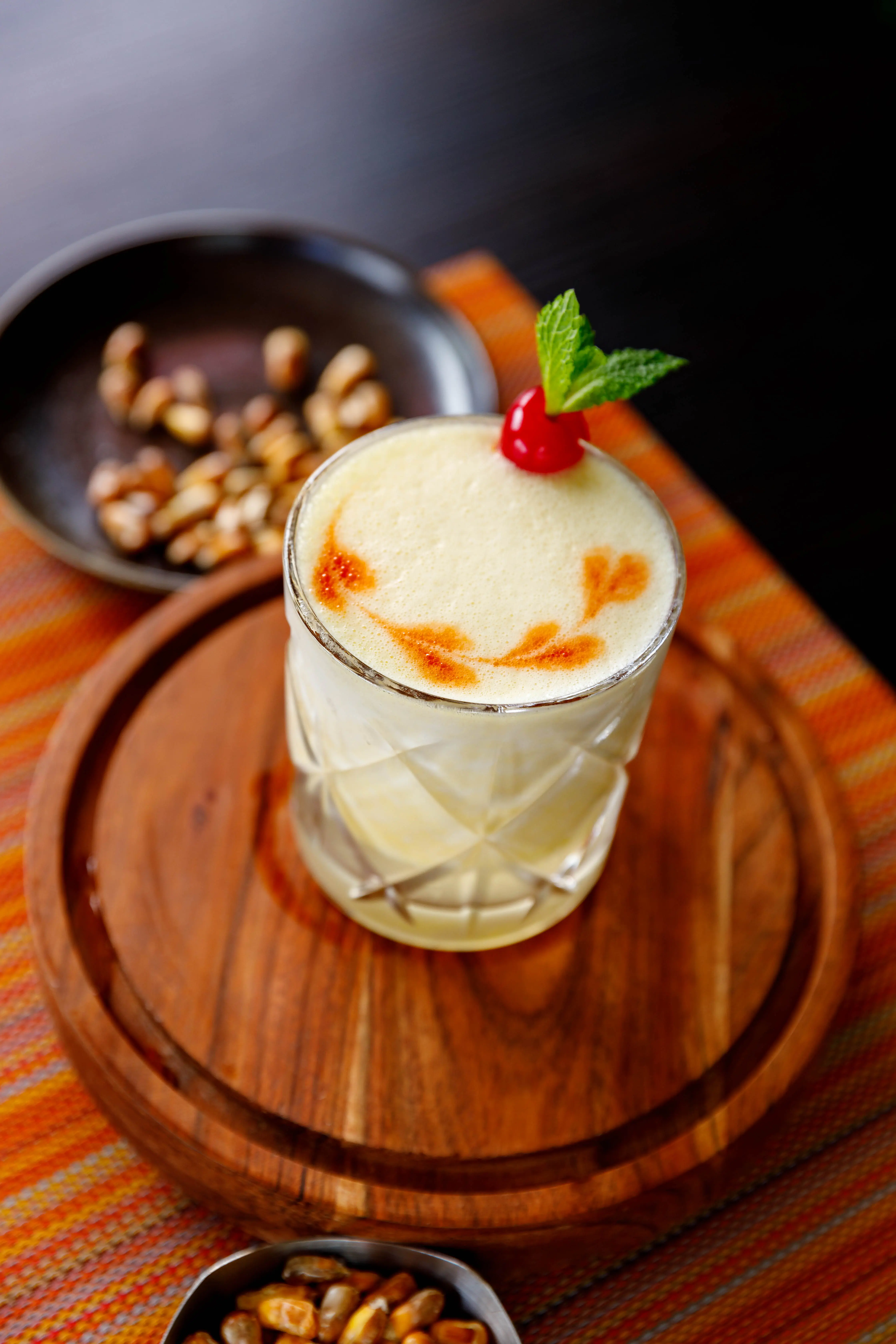 Cream-topped cocktail with a cherry served on a patterned runner