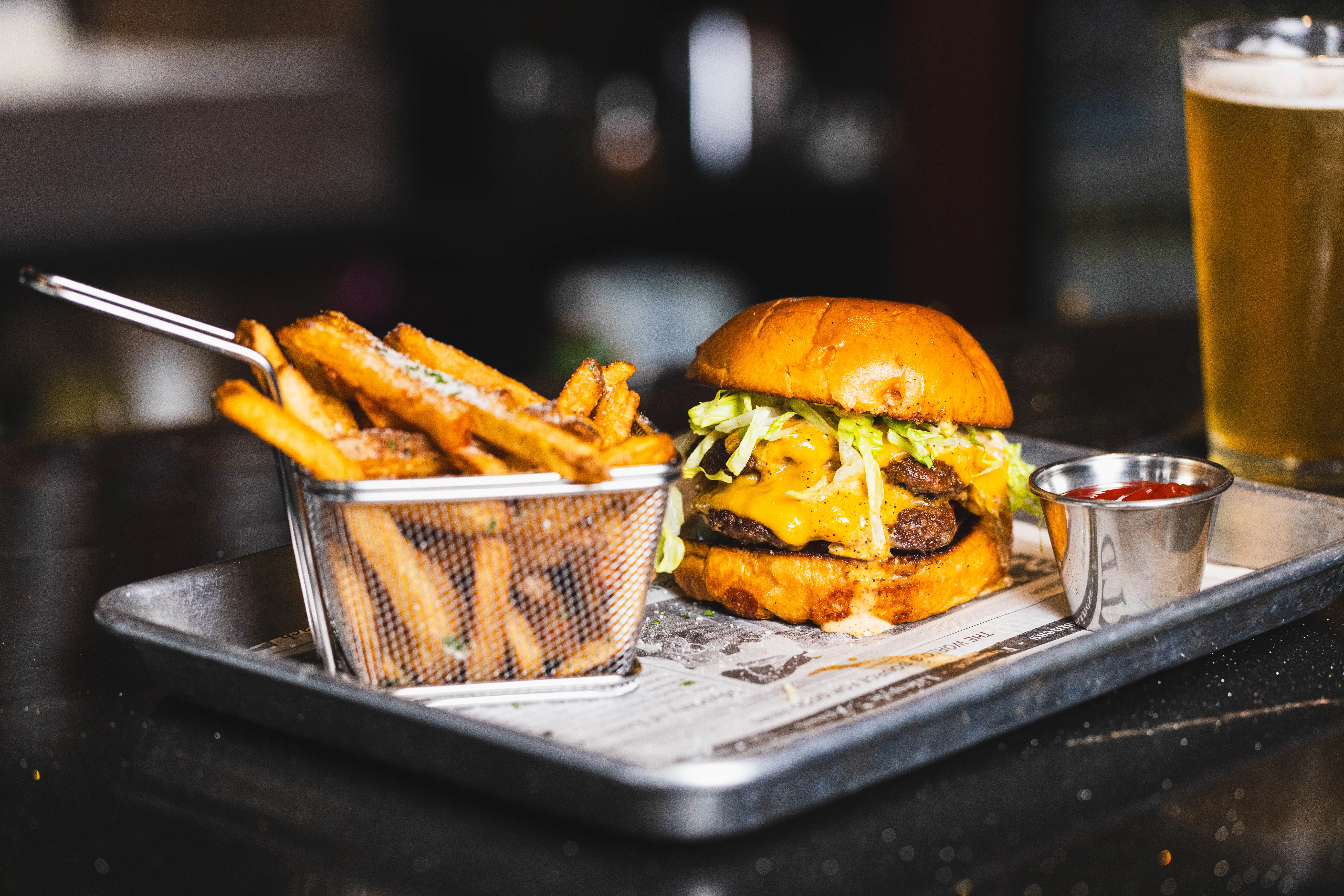 Cheeseburger with melted cheddar and shredded lettuce next to a fry basket