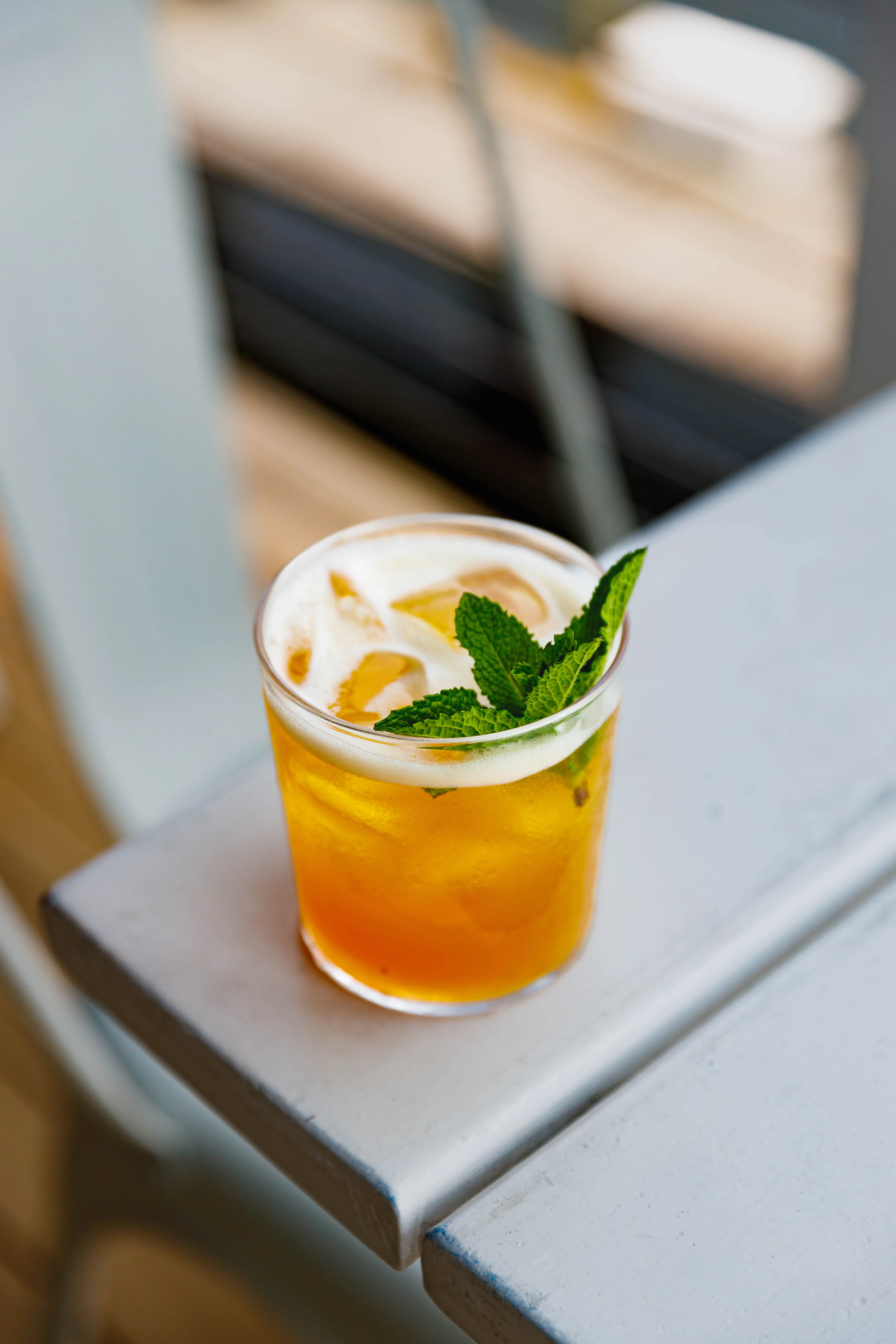 Iced cocktail with mint served on a metal counter in soft daylight
