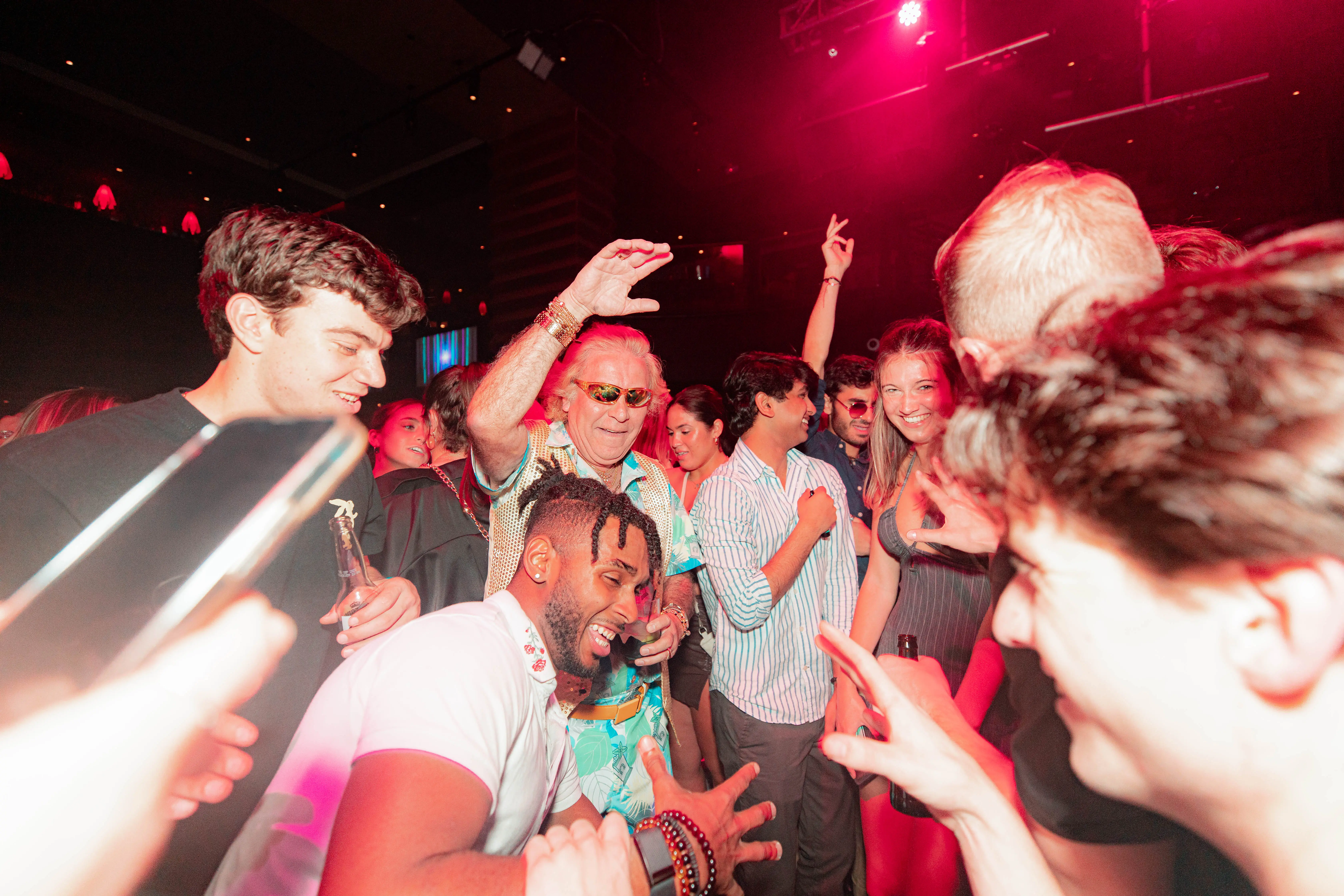 Friends dancing under pink and red lights at a late-night party