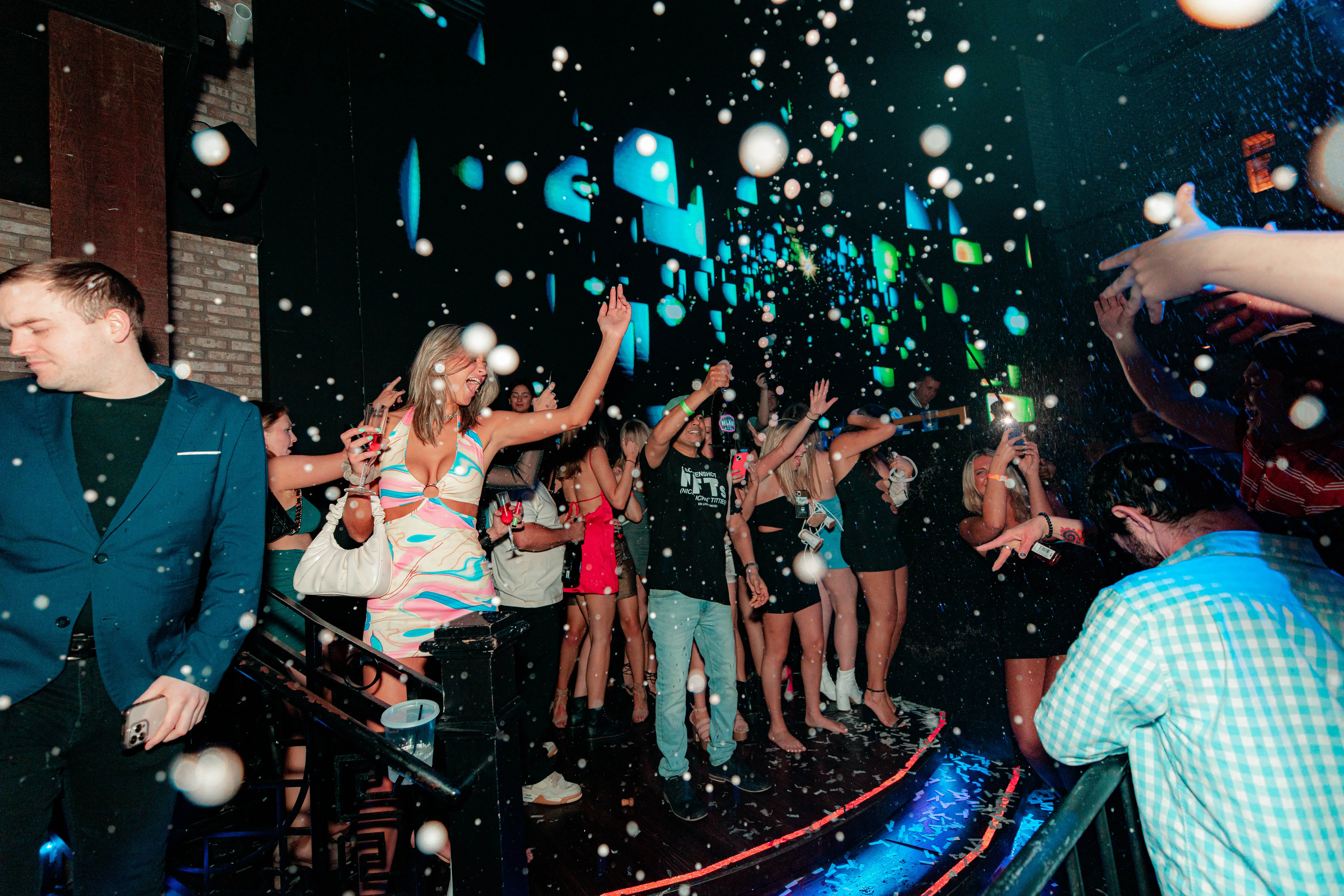 Wide view of streamers raining over a packed club crowd