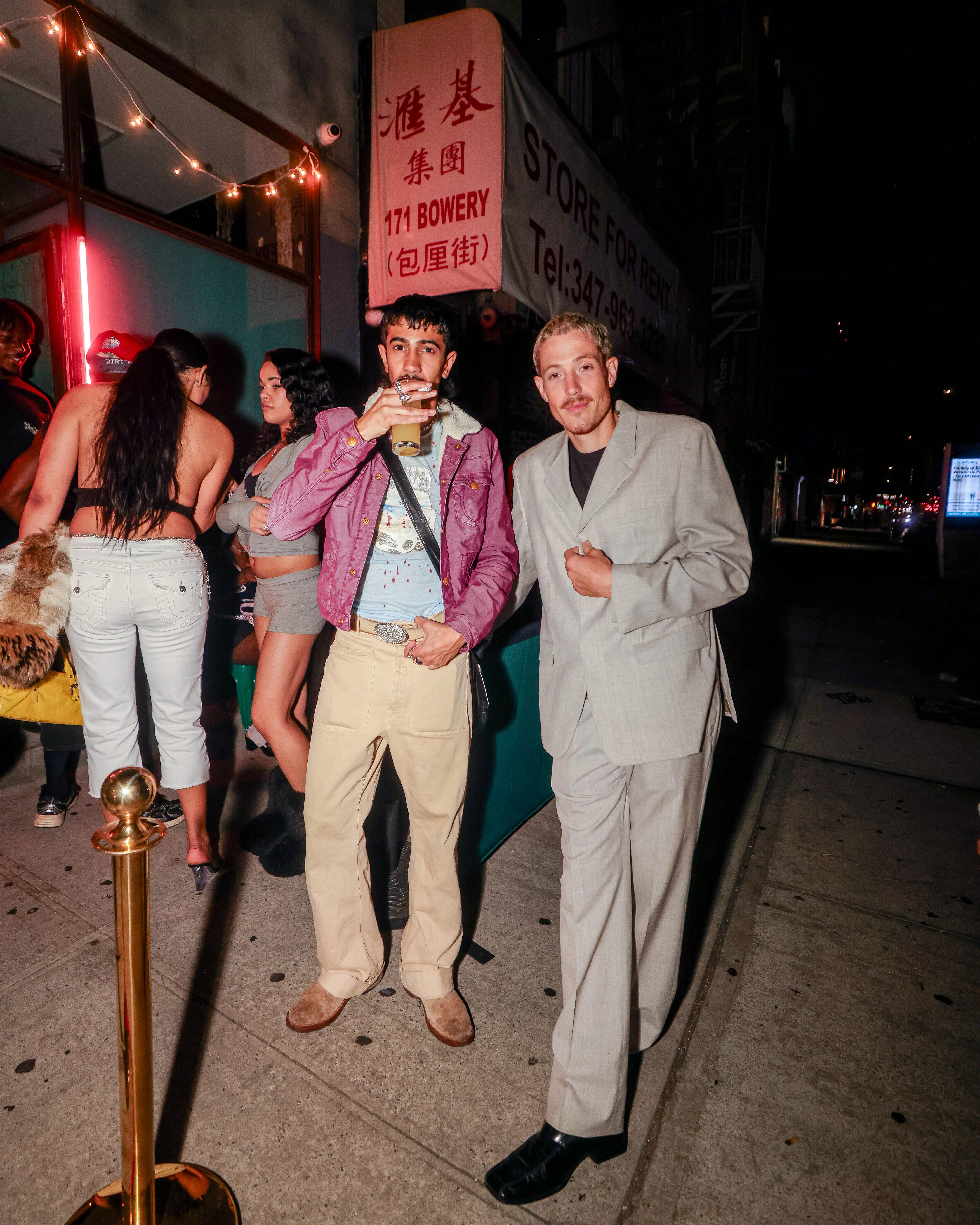 Two styled guests posing outside a storefront at night after an event